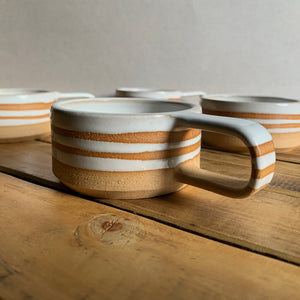 Brown stoneware espresso cup with glossy white interior and decorative stripes, group shot