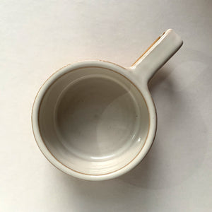 Brown stoneware espresso cup with glossy white interior and decorative stripes, top view